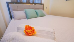 A neatly made bed with a single orange rose on the pillows and a folded white towel. - Lovely 2 Bd-2Bath Apt w. A|C Garage & Rooftop (San Cristobal)
