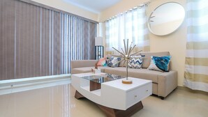 A modern living room with a glass coffee table, a beige sofa, and a large mirror on the wall. - Lovely 2 Bd-2Bath Apt w. A|C Garage & Rooftop (San Cristobal)