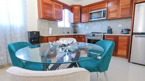 A modern kitchen with wooden cabinets, a glass dining table, and teal chairs. - Beautiful 2Bd/2bath apt W. AC, Garage  & roof top (San Cristobal)