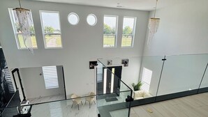 A modern interior with a glass staircase, multiple windows, and a view of the outdoors. - Peaceful Farmhouse Retreat in Van Alstyne (Van Alstyne)