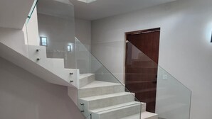 A modern staircase with glass railings and a wooden door at the top.