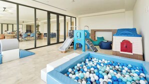 A spacious indoor play area with a ball pit, slides, and a playhouse.