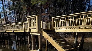 Un muelle de madera con una escalera que conduce a una plataforma, rodeado de árboles.