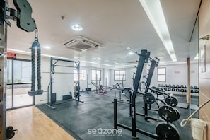 A gym with weightlifting equipment, cardio machines, and dumbbells.