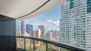 Een hoog gebouw met uitzicht op een stadsbeeld, met een balkon met een zwart betegelde muur en een metalen hekwerk.