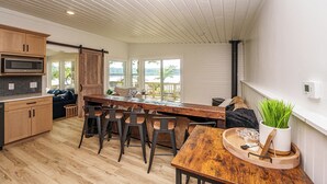 A modern kitchen with a central island, bar stools, and a view of the outdoors. - Lakefront | Sauna, Kayaks, Fire Pit, & Huge Deck (Mecosta)