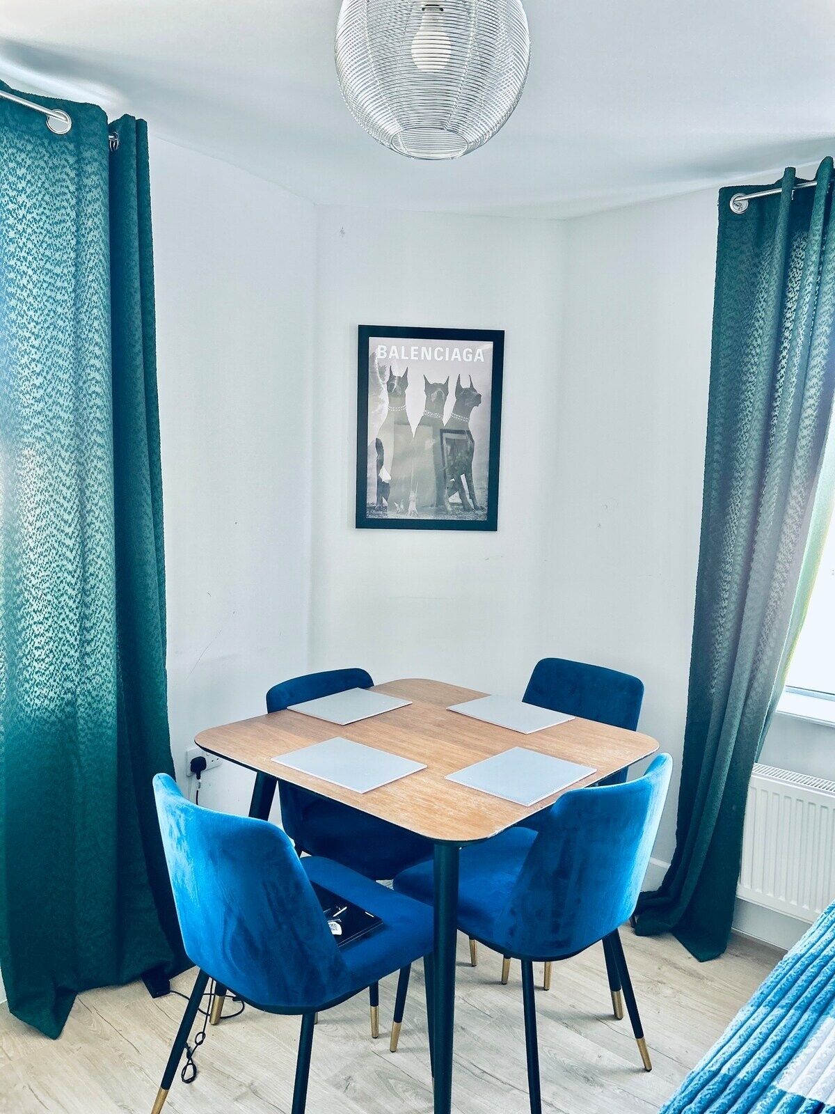 Ein Essbereich mit einem runden Tisch, vier blauen Stühlen und einem gerahmten Bild an der Wand.
