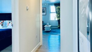 Un pasillo que lleva a un dormitorio con una cama y una mesita de noche.