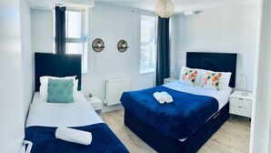 Habitación de hotel moderna con dos camas, un ventanal grande y vistas a la ciudad.