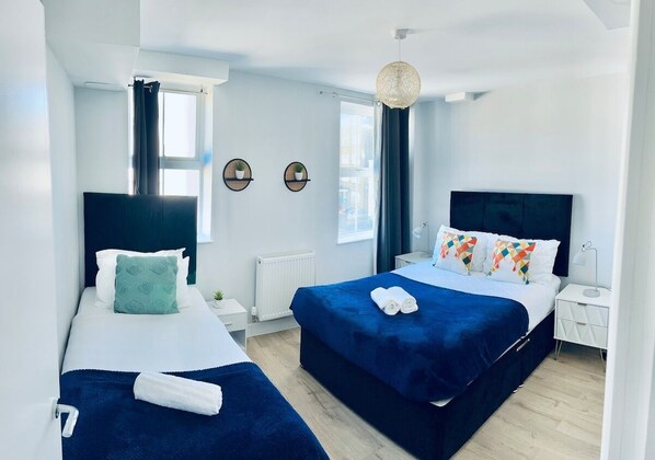A modern hotel room with two beds, a large window, and a view of the city.