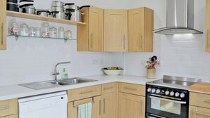 A modern kitchen with wooden cabinets, a stainless steel range hood, a dishwasher, and a double oven.
