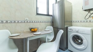 A compact kitchen with a washing machine, a dining table with chairs, and a window. - Pena View Apartment by Atlantic Holiday (Funchal)