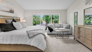 Un dormitorio con cama, sofá, mesa de centro y cómoda.