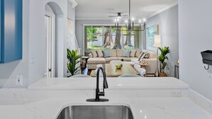 Una cocina moderna con encimera de mármol blanco, pileta de acero inoxidable y horno empotrado.