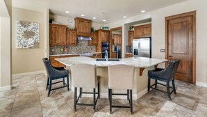 A kitchen with a central island, wooden cabinets, and a stainless steel refrigerator. - Havasu Duke - Pool, Spa, Basketball, Central (Lake Havasu City)