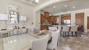 A spacious kitchen with wooden cabinets, a central island, and a dining area with a glass table and chairs. - Havasu Duke - Pool, Spa, Basketball, Central (Lake Havasu City)