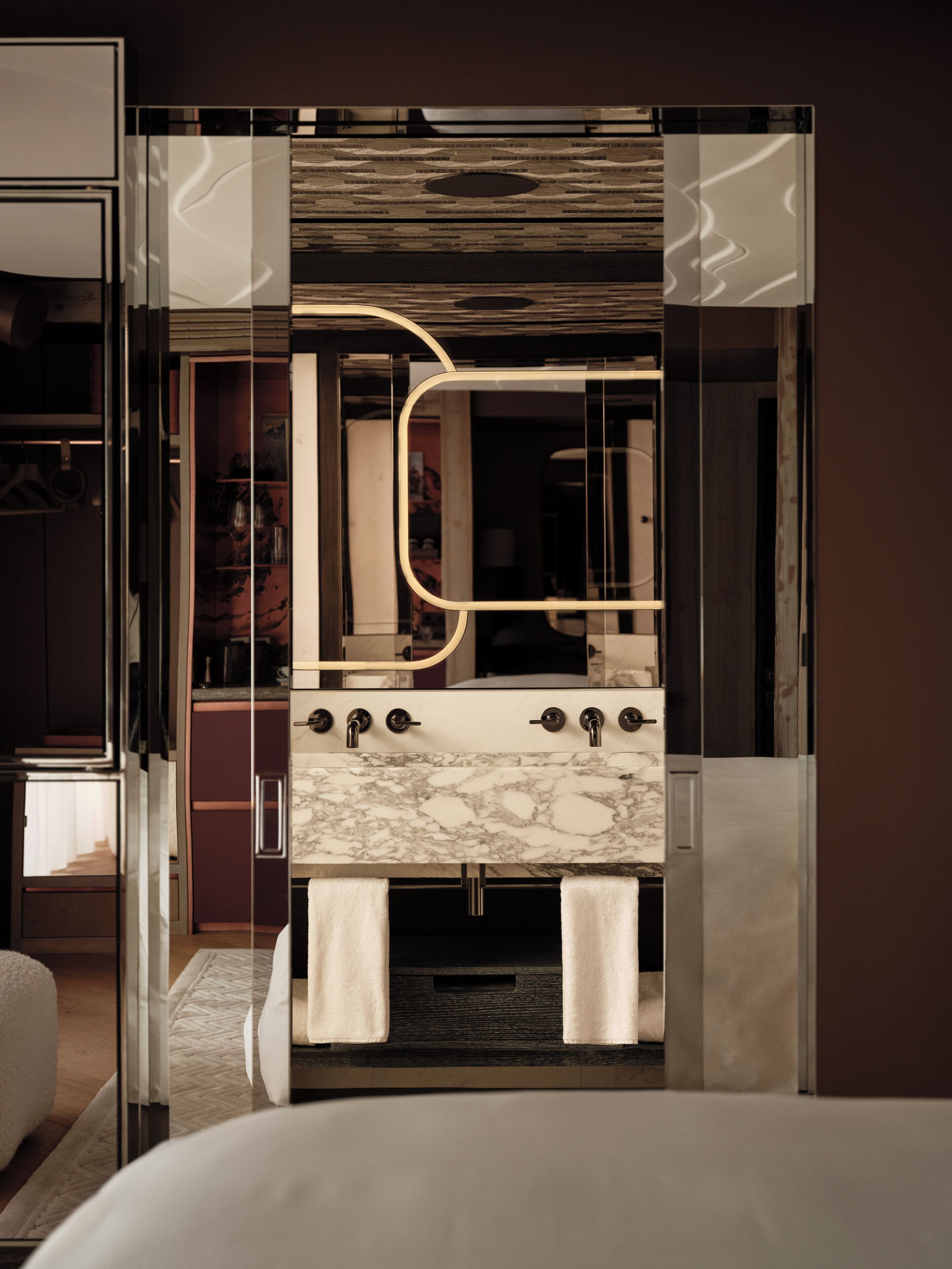 A modern bathroom with a marble sink, a large mirror, and a glass-enclosed shower area.