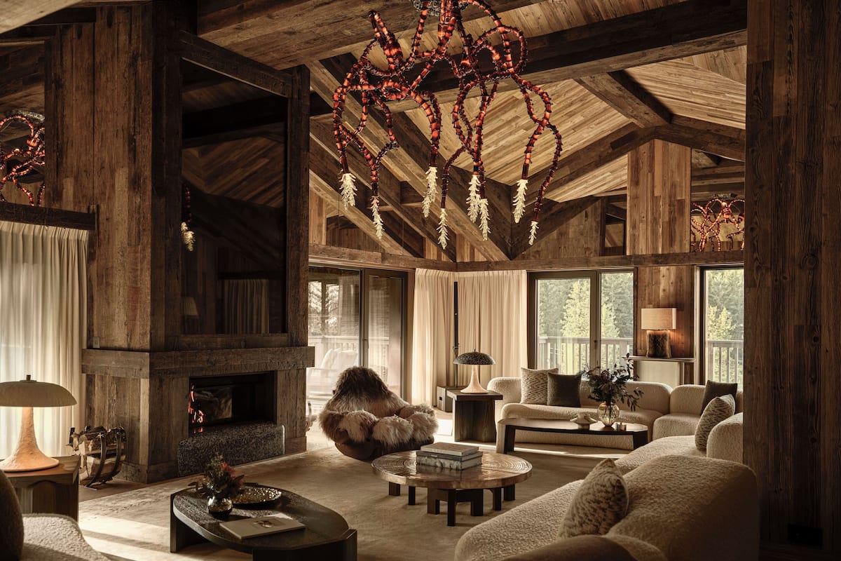 A rustic interior with wooden beams, a fireplace, and a cozy seating area with sofas and a coffee table.