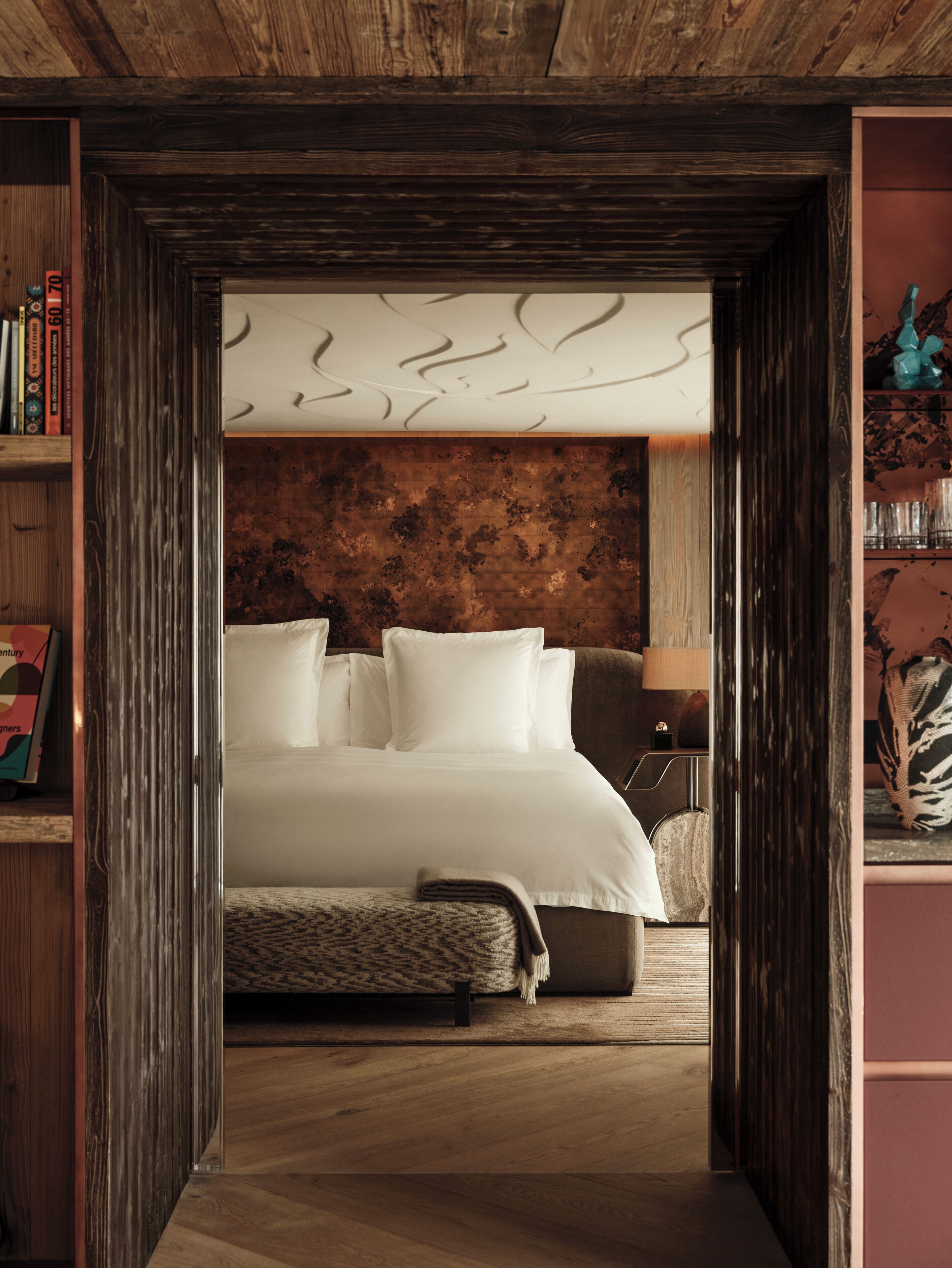 Une chambre à coucher avec une tête de lit en bois, un lit recouvert de draps blancs, une lampe de chevet et un petit tapis.