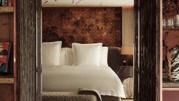 Une chambre à coucher avec une tête de lit en bois, un lit recouvert de draps blancs, une lampe de chevet et un petit tapis.