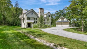 A two-story house with a stone chimney, a garage, and a well-maintained lawn.