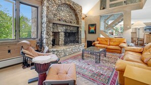A spacious living area with a stone fireplace, leather sofas, and a large window.