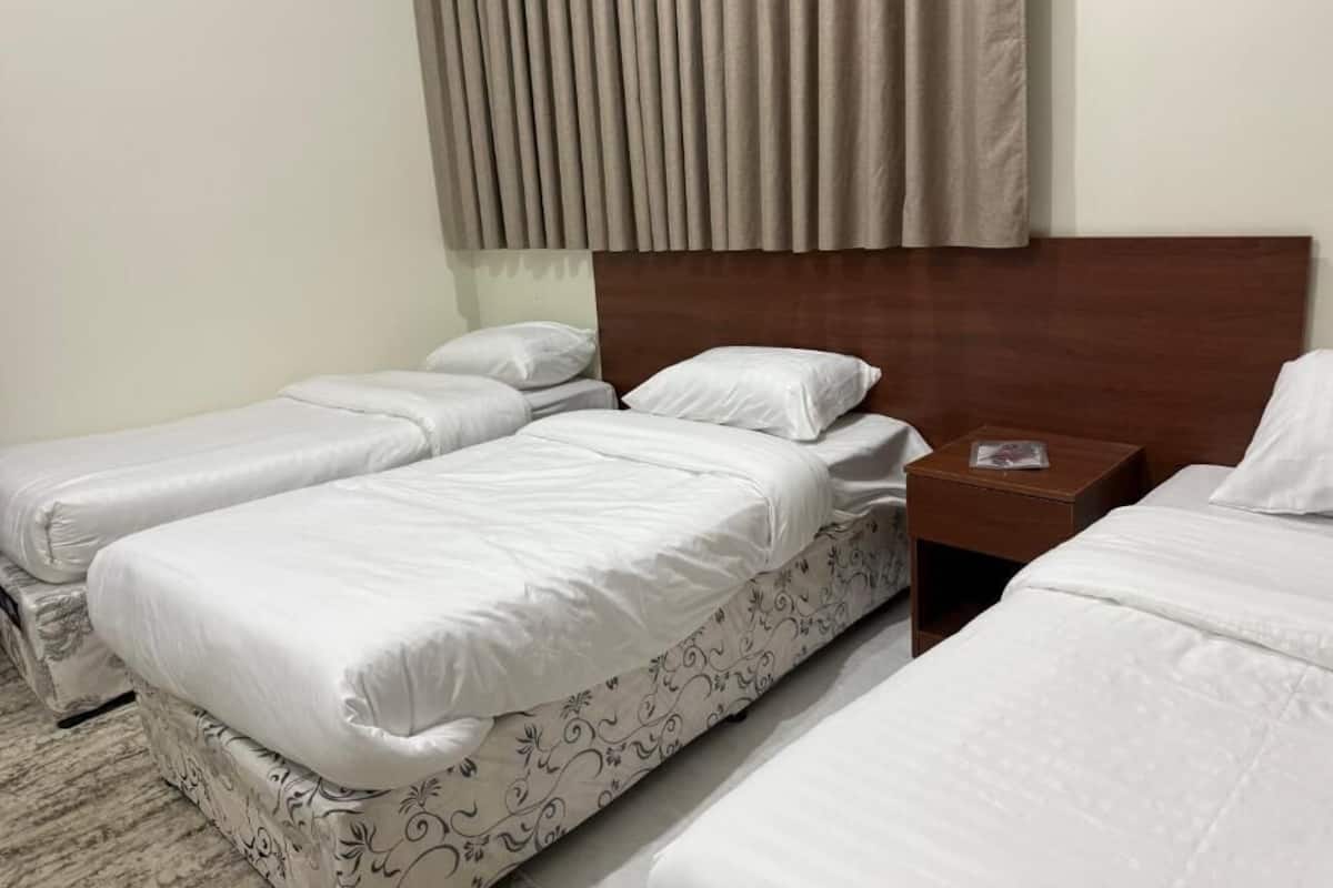 A hotel room with two single beds, a wooden headboard, and a nightstand with a lamp.