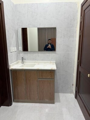 A bathroom with a wooden vanity, a mirror, and a white sink.