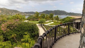 A scenic view from a balcony overlooking a landscaped garden with a pathway leading to a beach. - The Dream | Private 360° View Suite in Buck Island (Buck Island)