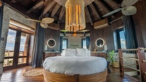 A circular wooden bed in a room with a high ceiling, large windows, and a view of the outdoors. - The Dream | Private 360° View Suite in Buck Island (Buck Island)