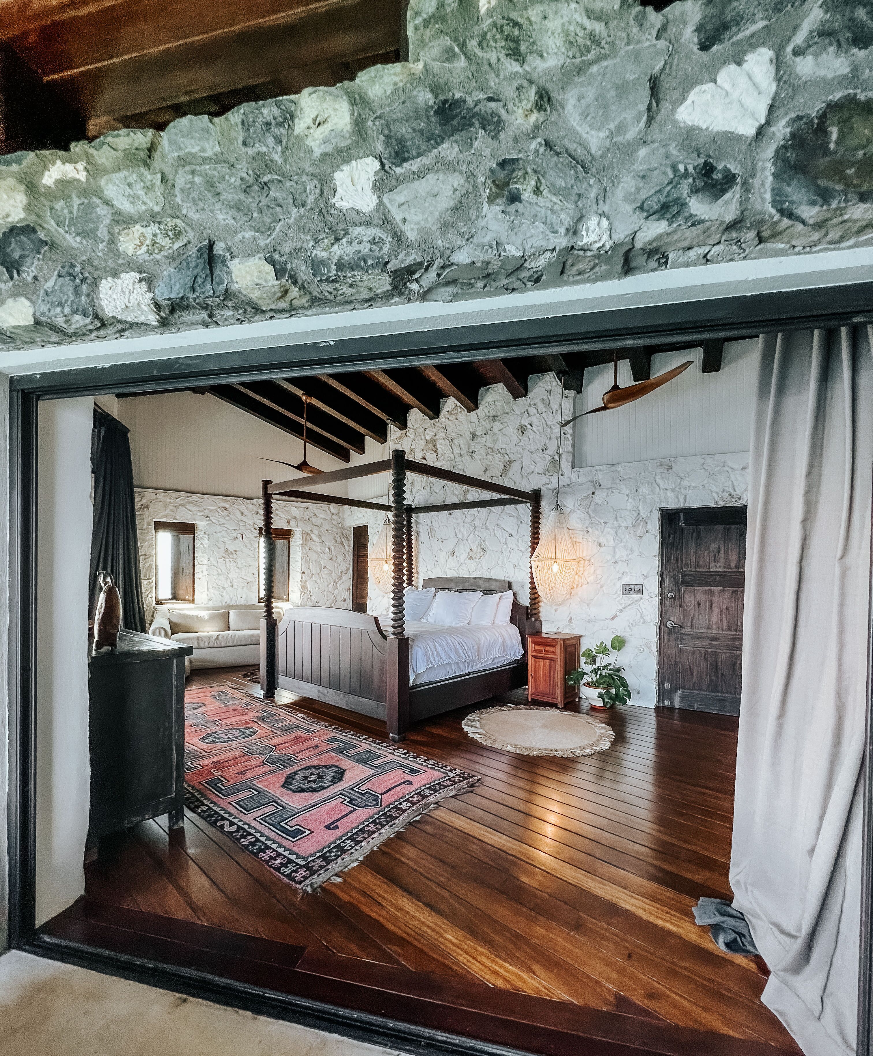 Un dormitorio con cama con dosel, pared de piedra y suelo de madera.