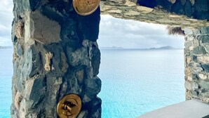 Un mur de pierre avec deux poignées de porte en laiton et une vue sur la mer.