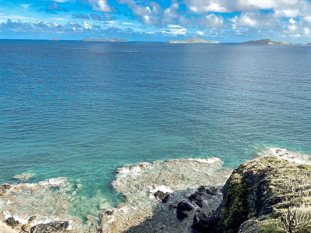 Un paisaje costero con aguas azul turquesa, costas rocosas e islas a lo lejos.