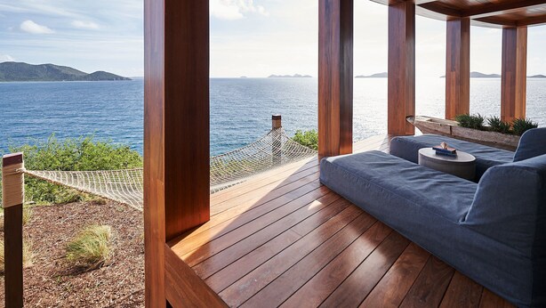 A wooden deck with a blue sofa and a small round table, overlooking a body of water and distant land. - Breakfast Incl | Caribbean Escape | Ocean Views (Buck Island)