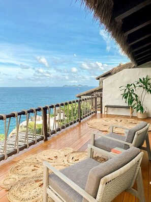 A wooden deck with wicker furniture and a view of the ocean.
