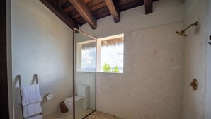 A bathroom with a shower, a toilet, a towel rack, and a window with a view.