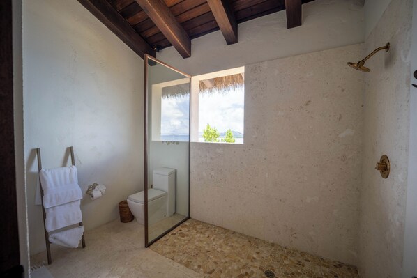 A bathroom with a shower, a toilet, a towel rack, and a window with a view.