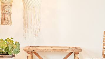 Een rustieke houten tafel met een geweven vloerkleed, een potplant en twee macramé wanddecoraties.