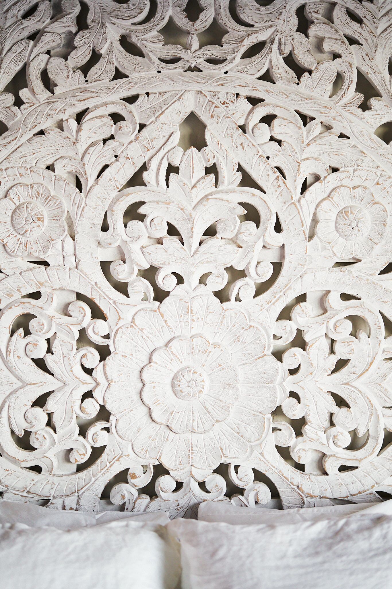 Un panneau en bois sculpté et peint en blanc, orné de motifs floraux et de feuilles.