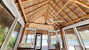 A room with a thatched roof, a bed, a ceiling fan, and a view of the sea. - Secluded Beachfront Teepee Villa w/ Ocean Views (Buck Island)