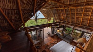 Quarto espaçoso com uma cama grande, área de estar e vista para o exterior.