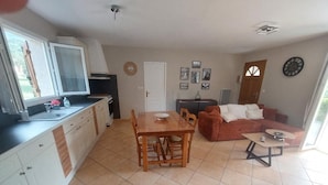 Une cuisine avec une table à manger et des chaises, un canapé, une petite table et une fenêtre.