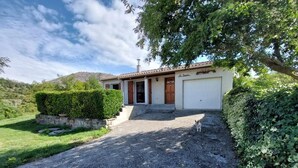 Une maison de plain-pied à l’extérieur blanc, avec un toit recouvert de tuiles rouges et un portail de garage à l’avant.