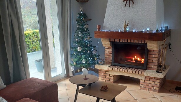 Un salon avec une cheminée, un sapin de Noël et un canapé.