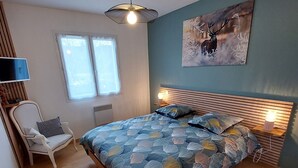 Une chambre à coucher avec un lit, une chaise, une télévision et une fenêtre.
