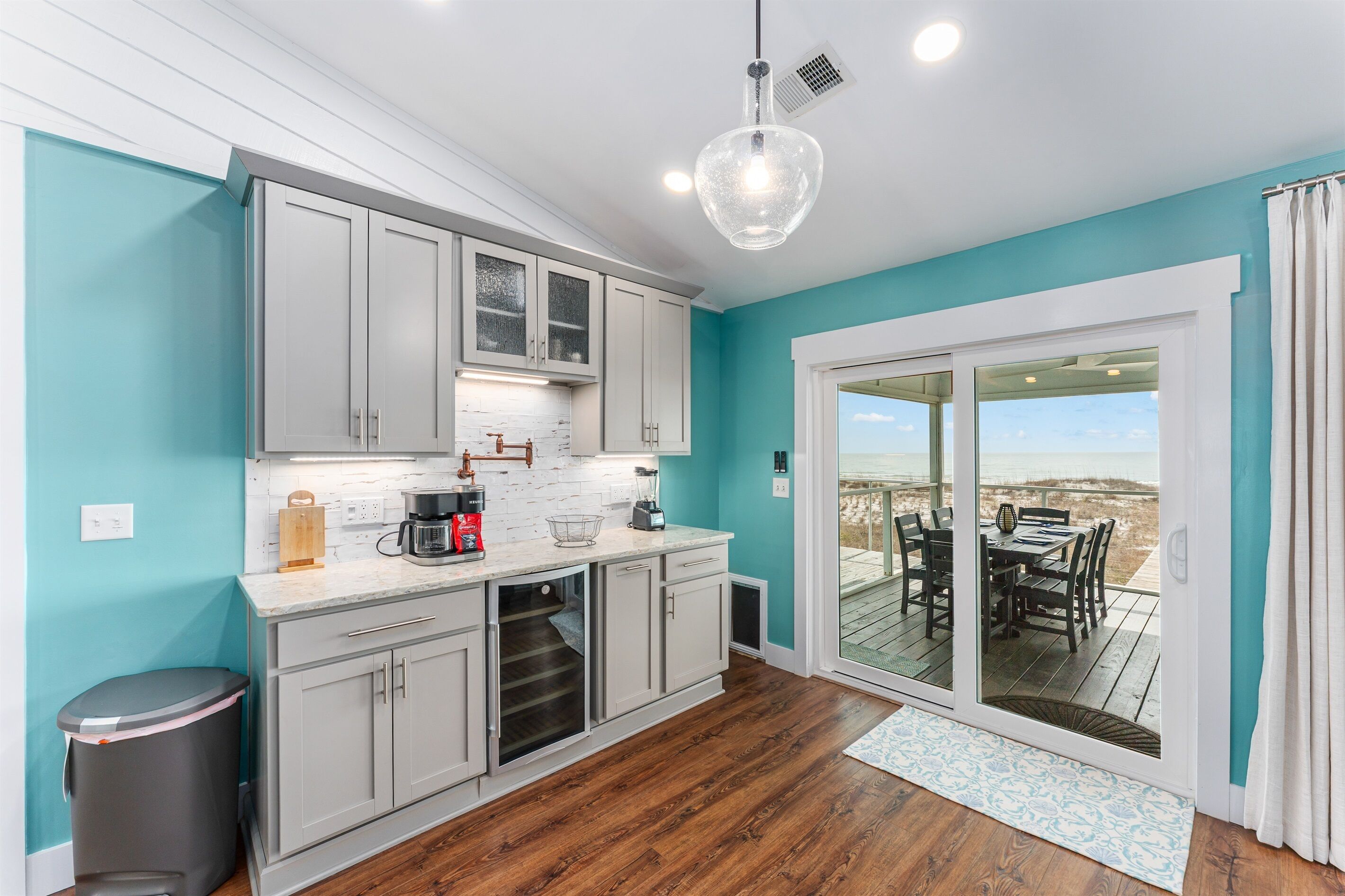 A kitchen with white cabinets, a wooden countertop, and a view to an outdoor deck.