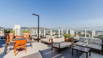 Eine Dachterrasse mit Gartenmöbeln, Topfpflanzen und Blick auf die Stadt.