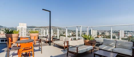 Terraza en la azotea con mobiliario exterior, plantas en macetas y vistas a la ciudad.