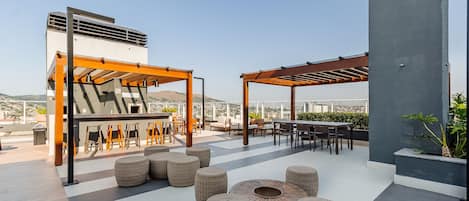 An outdoor patio area with wicker furniture, a pergola, and a view of the cityscape.