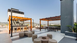 A rooftop terrace with outdoor seating, a pergola, and a view of the cityscape. - Studio in Building With Pool Con1206 (Porto Alegre)